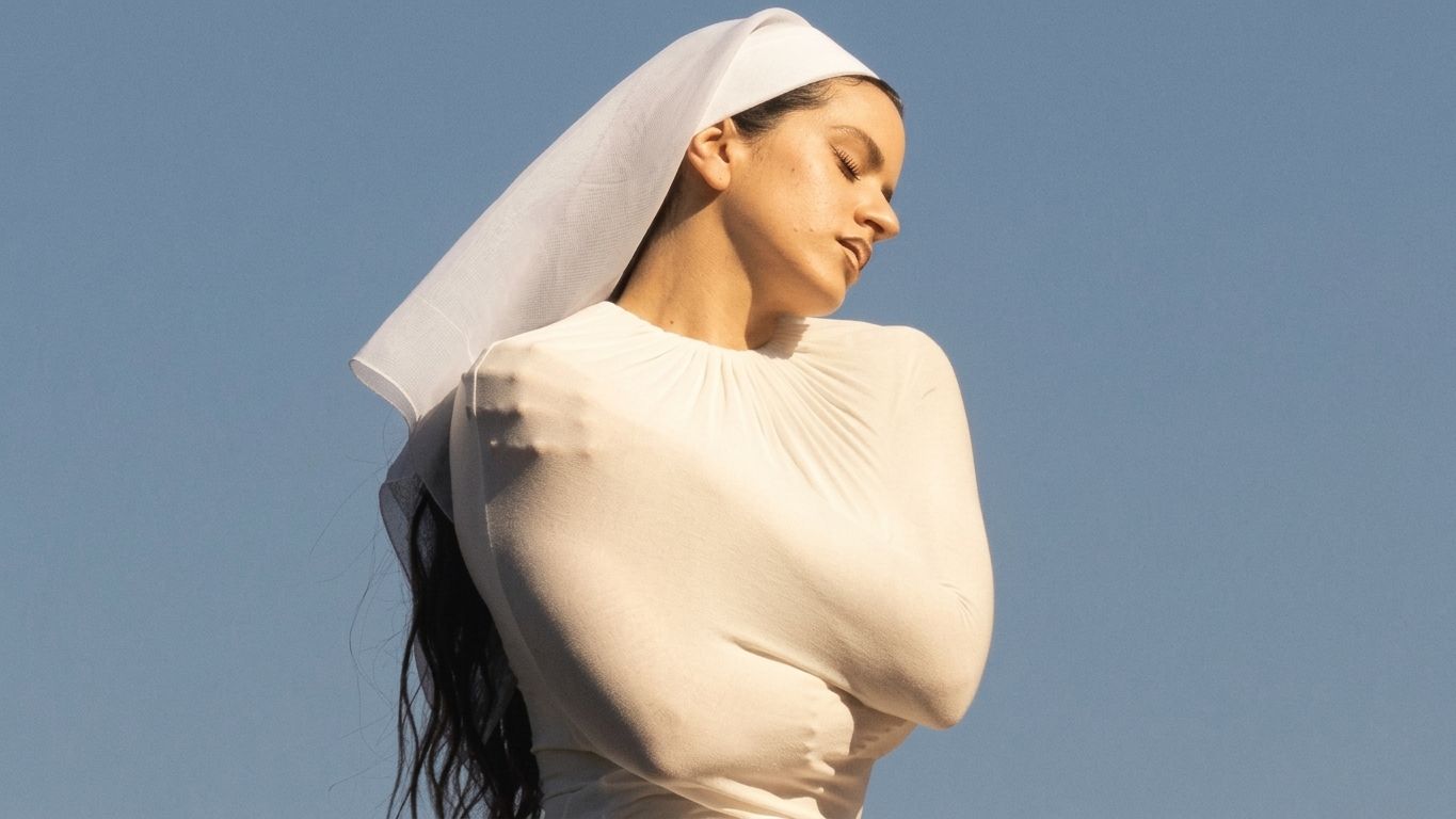 Rosalía de blanco, con un velo y los ojos cerrados, bajo un cielo celeste